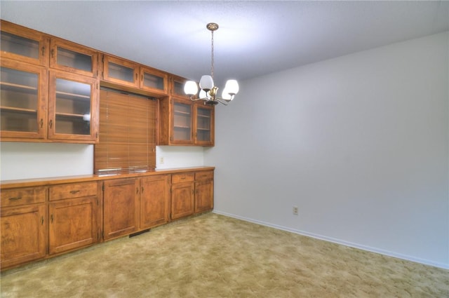 325 S Durfee St, Warrensburg, IL 62573 - kitchen with a chandelier, hanging light fixtures, brown cabinetry, glass insert cabinets, and light carpet