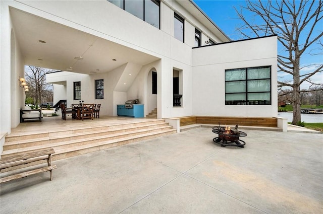 9219 E Best Ct, Effingham, IL 62401 - rear view of house with stucco siding, a fire pit, a patio, and outdoor dining area