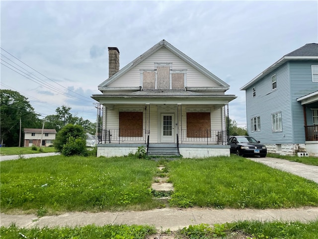 bungalow-style home with covered porch and a front yard