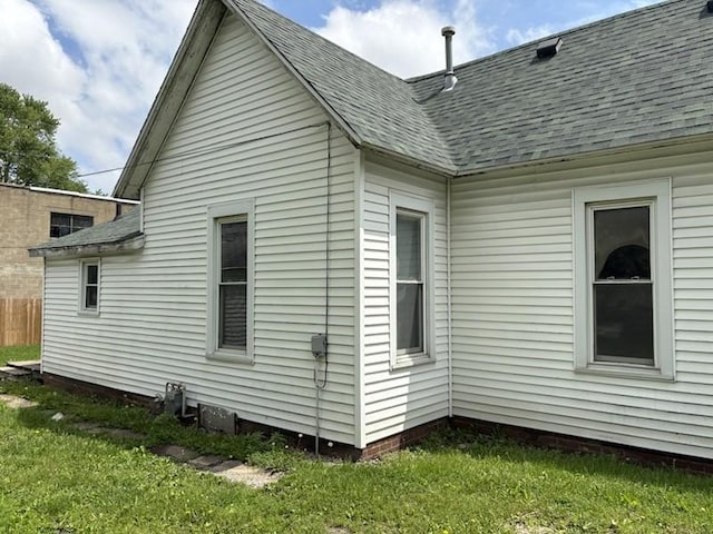 view of home's exterior with a yard and roof with shingles