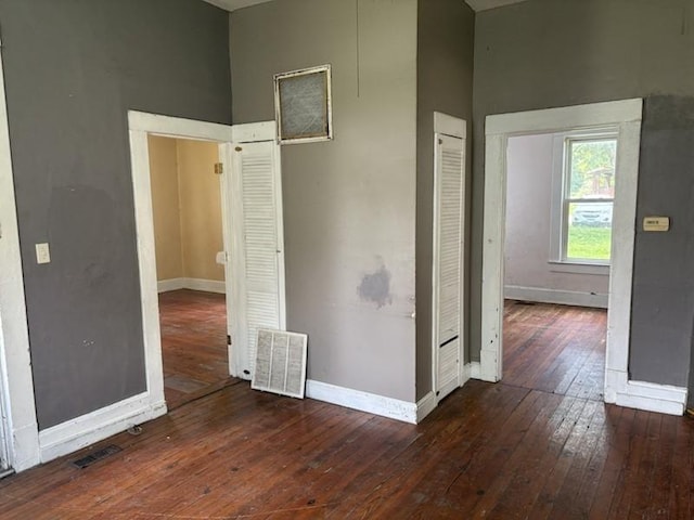 spare room with hardwood / wood-style floors, a towering ceiling, and baseboards