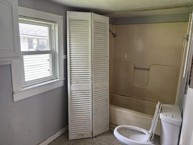 bathroom featuring toilet, tile patterned flooring, and bathing tub / shower combination