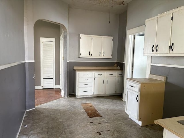 kitchen with arched walkways, baseboards, and white cabinetry
