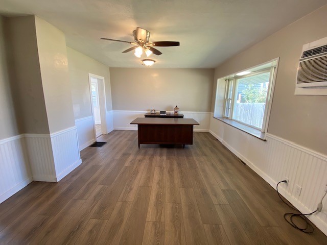 office space featuring a wall mounted air conditioner, ceiling fan, and dark hardwood / wood-style flooring