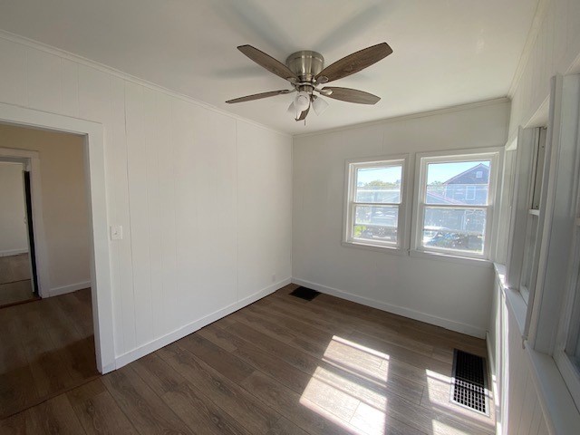 unfurnished room with ceiling fan, dark wood-type flooring, and ornamental molding