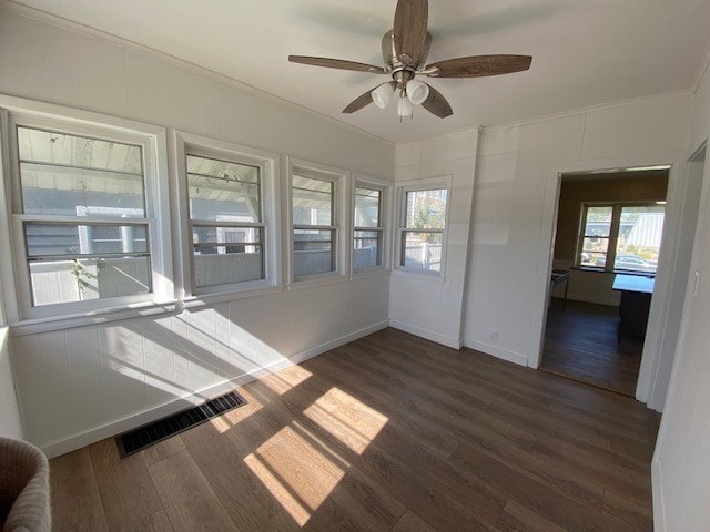 empty room featuring dark hardwood / wood-style floors, crown molding, and a wealth of natural light