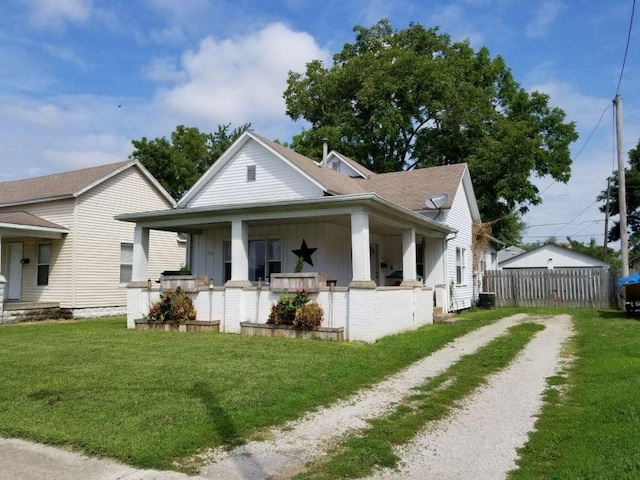 bungalow-style home featuring a porch, fence, board and batten siding, and a front yard