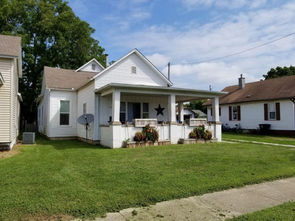 bungalow-style home featuring a porch, central AC, board and batten siding, and a front yard