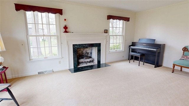 sitting room featuring crown molding, a premium fireplace, visible vents, and carpet