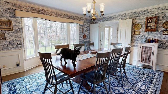 dining space featuring a wainscoted wall, ornamental molding, wallpapered walls, and wood finished floors