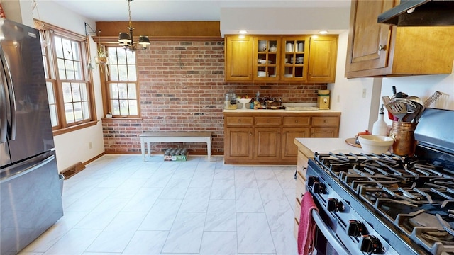 kitchen with under cabinet range hood, brown cabinets, appliances with stainless steel finishes, and marble finish floor