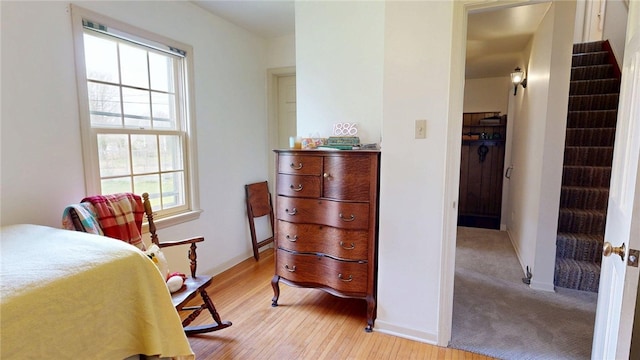 bedroom with baseboards, multiple windows, and light wood finished floors