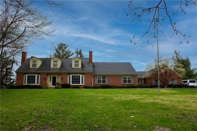 cape cod-style house featuring brick siding, a chimney, and a front yard