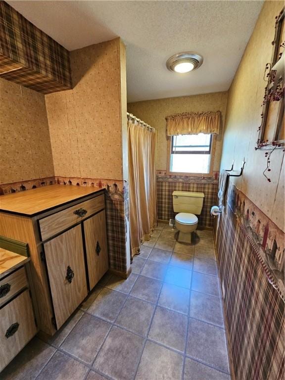 full bathroom featuring toilet, curtained shower, a textured ceiling, tile walls, and tile patterned flooring