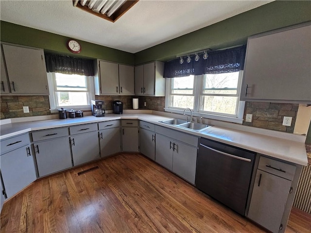 kitchen featuring wood finished floors, visible vents, a sink, light countertops, and stainless steel dishwasher