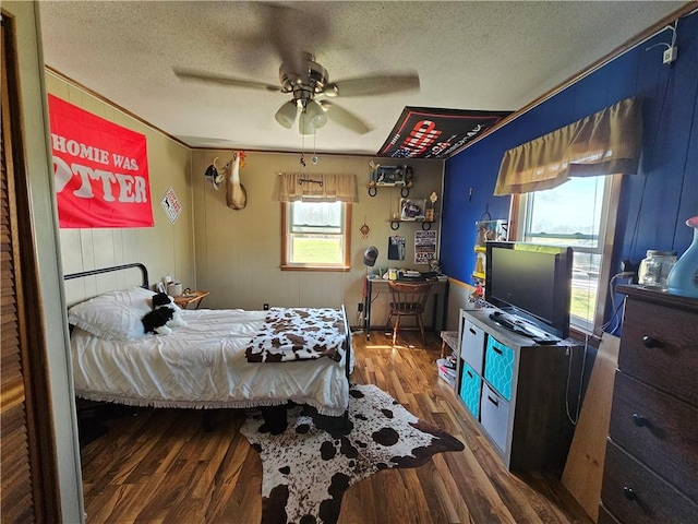 bedroom with ceiling fan, wood finished floors, and a textured ceiling