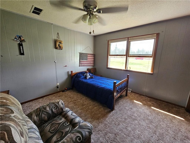 bedroom featuring a ceiling fan, carpet, visible vents, and a textured ceiling