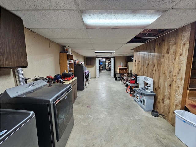 finished below grade area featuring a drop ceiling, washer / clothes dryer, and wooden walls