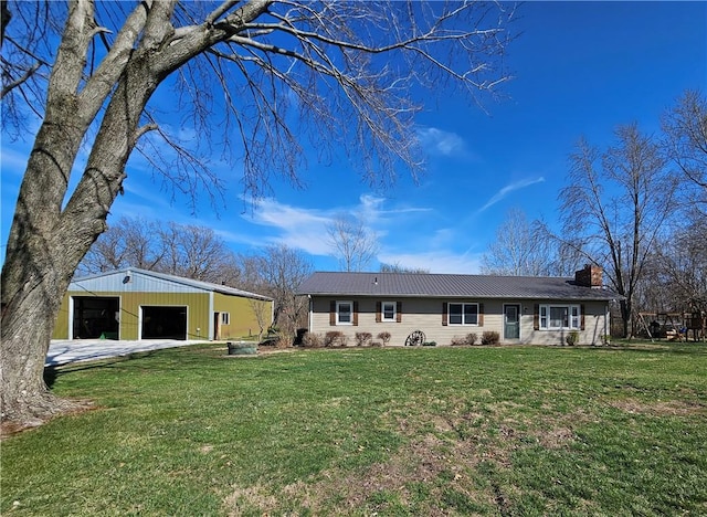 ranch-style house with a front yard, a chimney, a garage, an outbuilding, and driveway