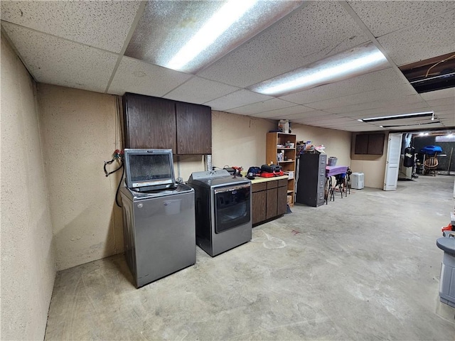 laundry room featuring cabinet space, a textured wall, and washing machine and clothes dryer