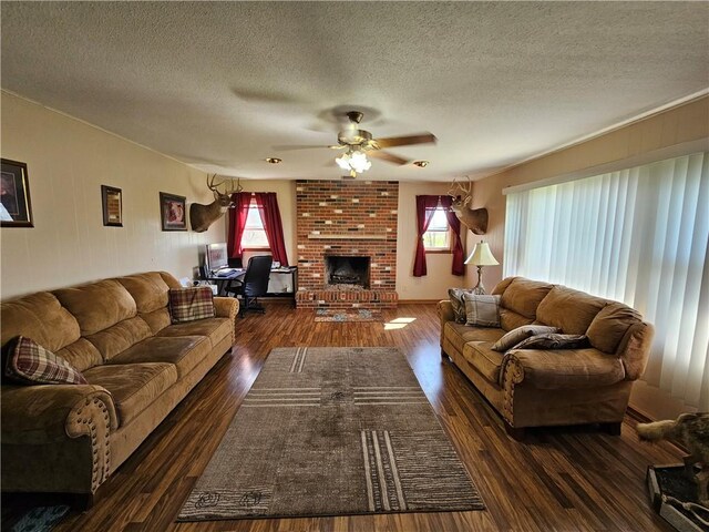 living area featuring a wealth of natural light, a fireplace, dark wood-type flooring, and a ceiling fan
