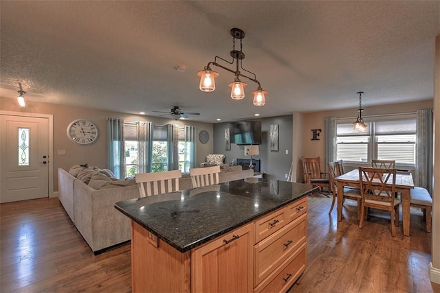 kitchen featuring dark stone countertops, a center island, hanging light fixtures, and a wealth of natural light