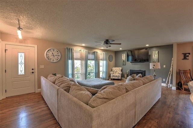 living room with ceiling fan, dark hardwood / wood-style floors, and a textured ceiling