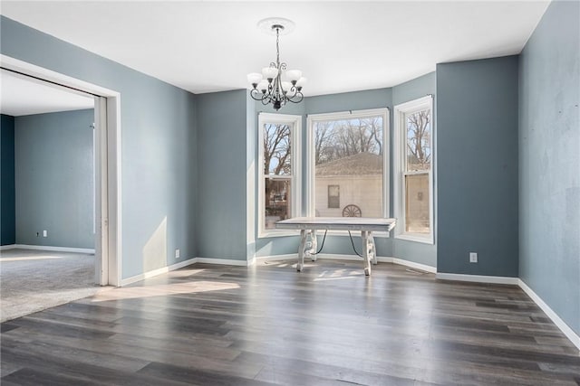 unfurnished dining area with dark wood-type flooring and an inviting chandelier