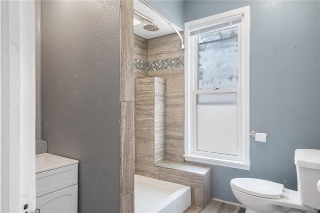 bathroom with tiled shower, vanity, and toilet