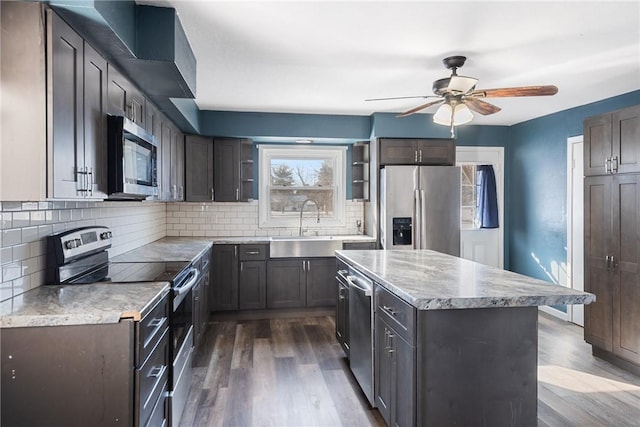 kitchen with stainless steel appliances, a kitchen island, sink, and dark wood-type flooring