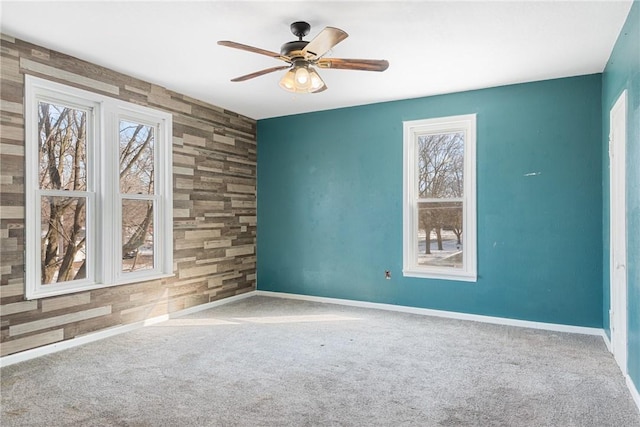 carpeted spare room with ceiling fan and plenty of natural light