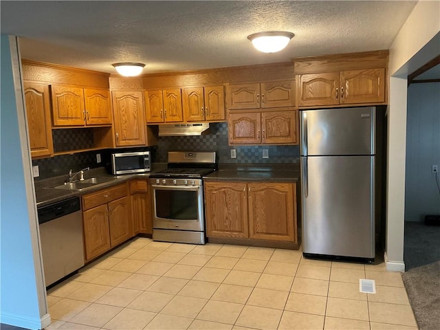 1696 W Evandale Dr, Decatur, IL 62526 - kitchen featuring appliances with stainless steel finishes, under cabinet range hood, dark countertops, backsplash, and a textured ceiling