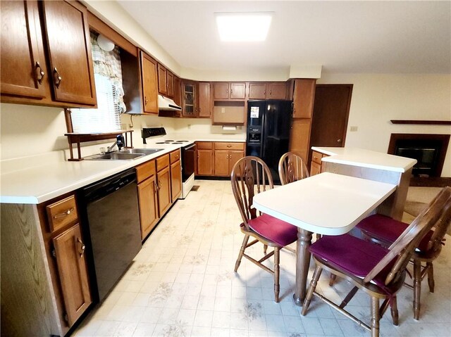 803 S Lafayette St, Newton, IL 62448 - kitchen with black appliances, under cabinet range hood, light countertops, a fireplace, and glass insert cabinets