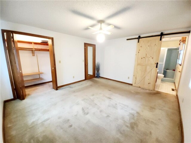 803 S Lafayette St, Newton, IL 62448 - unfurnished bedroom with a barn door, carpet floors, connected bathroom, a closet, and ceiling fan
