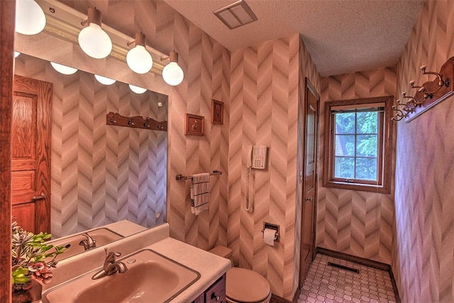 bathroom with tile patterned floors, vanity, toilet, and a textured ceiling