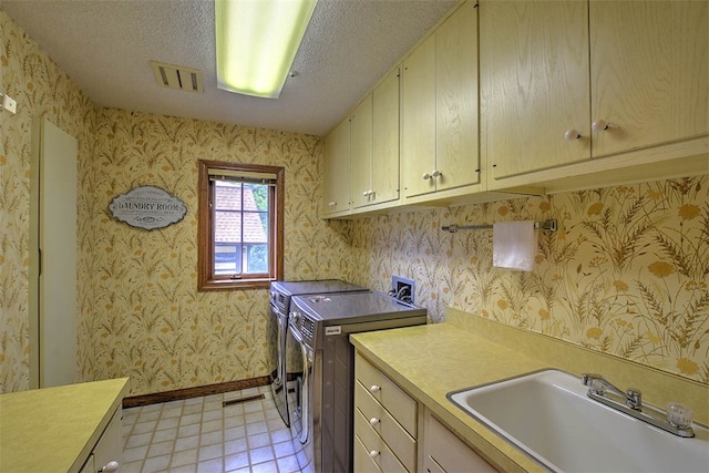 clothes washing area with washer and dryer, sink, cabinets, and a textured ceiling