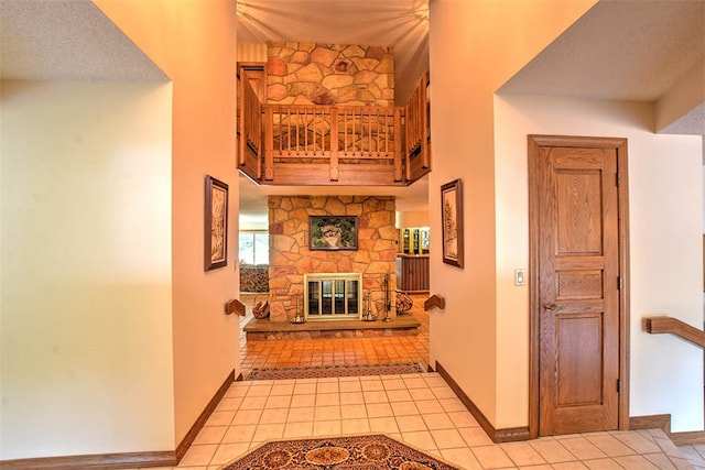 hallway featuring a towering ceiling, light tile patterned floors, and a textured ceiling