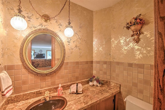 bathroom featuring vanity, tile walls, and toilet