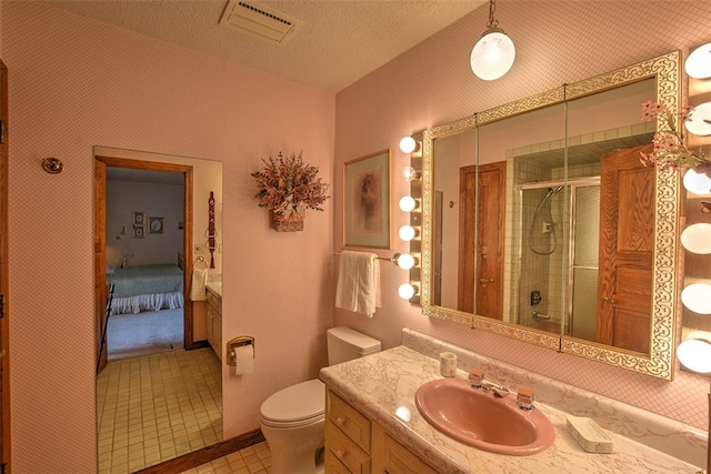 bathroom featuring tile patterned floors, vanity, a textured ceiling, toilet, and a shower with shower door