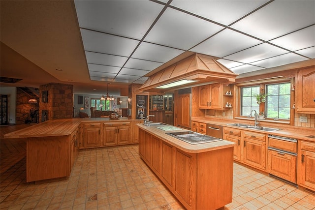 kitchen featuring a center island with sink, sink, and hanging light fixtures