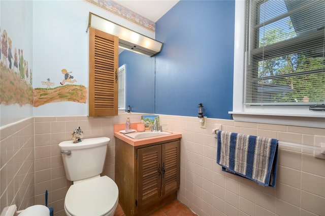 bathroom with tile patterned flooring, vanity, toilet, and tile walls