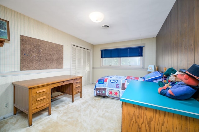 carpeted bedroom with a closet and wooden walls