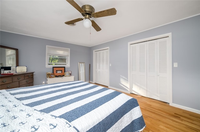 bedroom featuring ceiling fan, two closets, and light hardwood / wood-style flooring