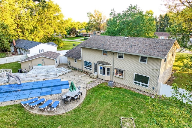 back of house featuring a yard, a covered pool, a patio area, and central air condition unit