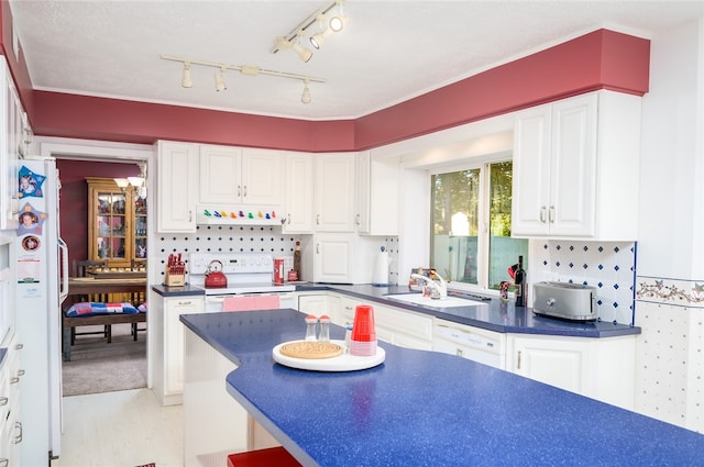 kitchen with kitchen peninsula, tasteful backsplash, white appliances, sink, and white cabinetry