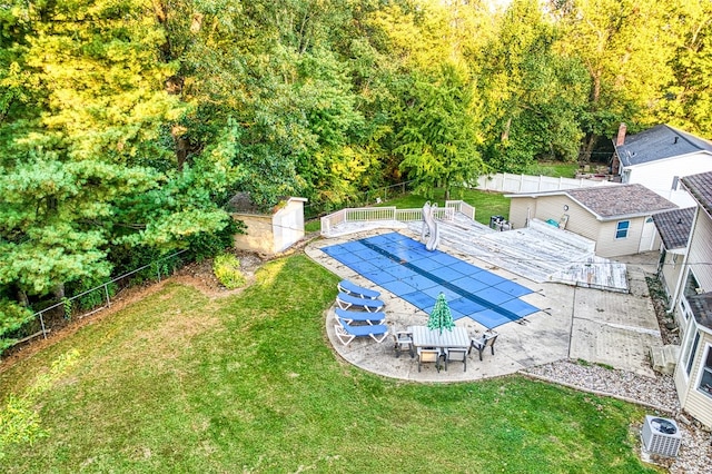 view of swimming pool with a lawn, a patio area, ac unit, and a storage shed