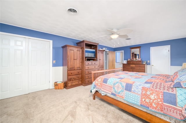 bedroom featuring ceiling fan, light colored carpet, wooden walls, and a closet