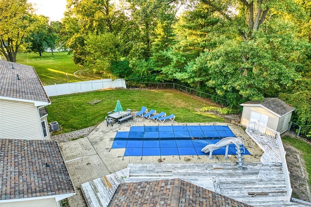 view of swimming pool with a storage shed, a yard, a patio, and a water slide