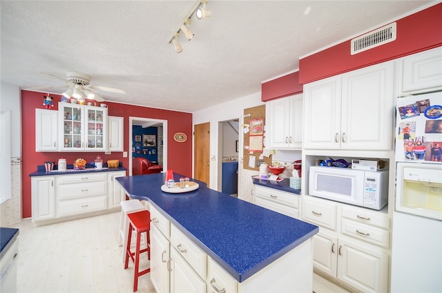 kitchen featuring a kitchen island, white appliances, white cabinetry, and light hardwood / wood-style flooring