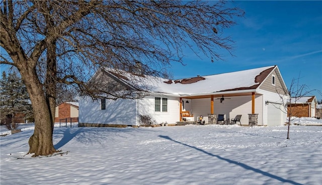 snow covered property featuring ceiling fan and a garage